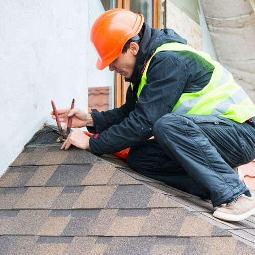 A roofer repairs shingles.