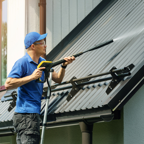 Roofer cleans a metal roof