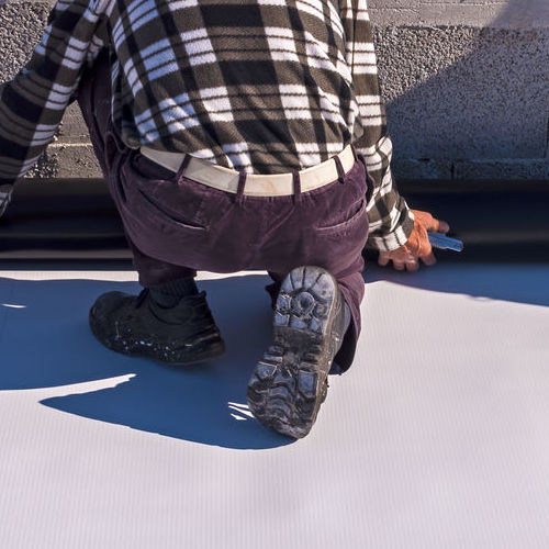 Roofer installs PVC on a flat roof.